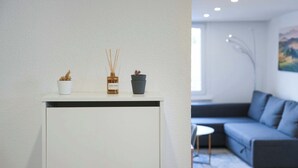 A modern living room with a white console table, a grey sofa, and a small round table.