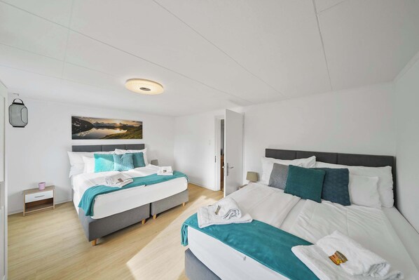 Una habitación de hotel moderna con dos camas, un ventanal grande y un cuadro en la pared.