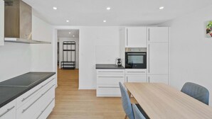 A modern kitchen with white cabinets, a black countertop, and a wooden dining table.