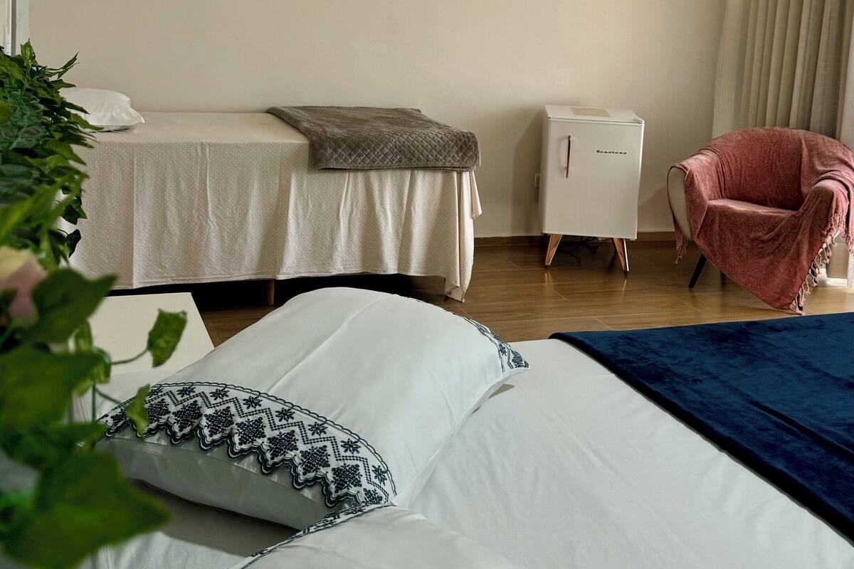 A hotel room with two beds, a small desk, a chair, and a painting on the wall.