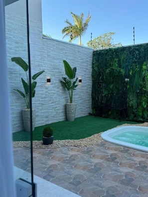 Un espace extérieur moderne avec une terrasse en pierre, une petite piscine et des plantes en pot.