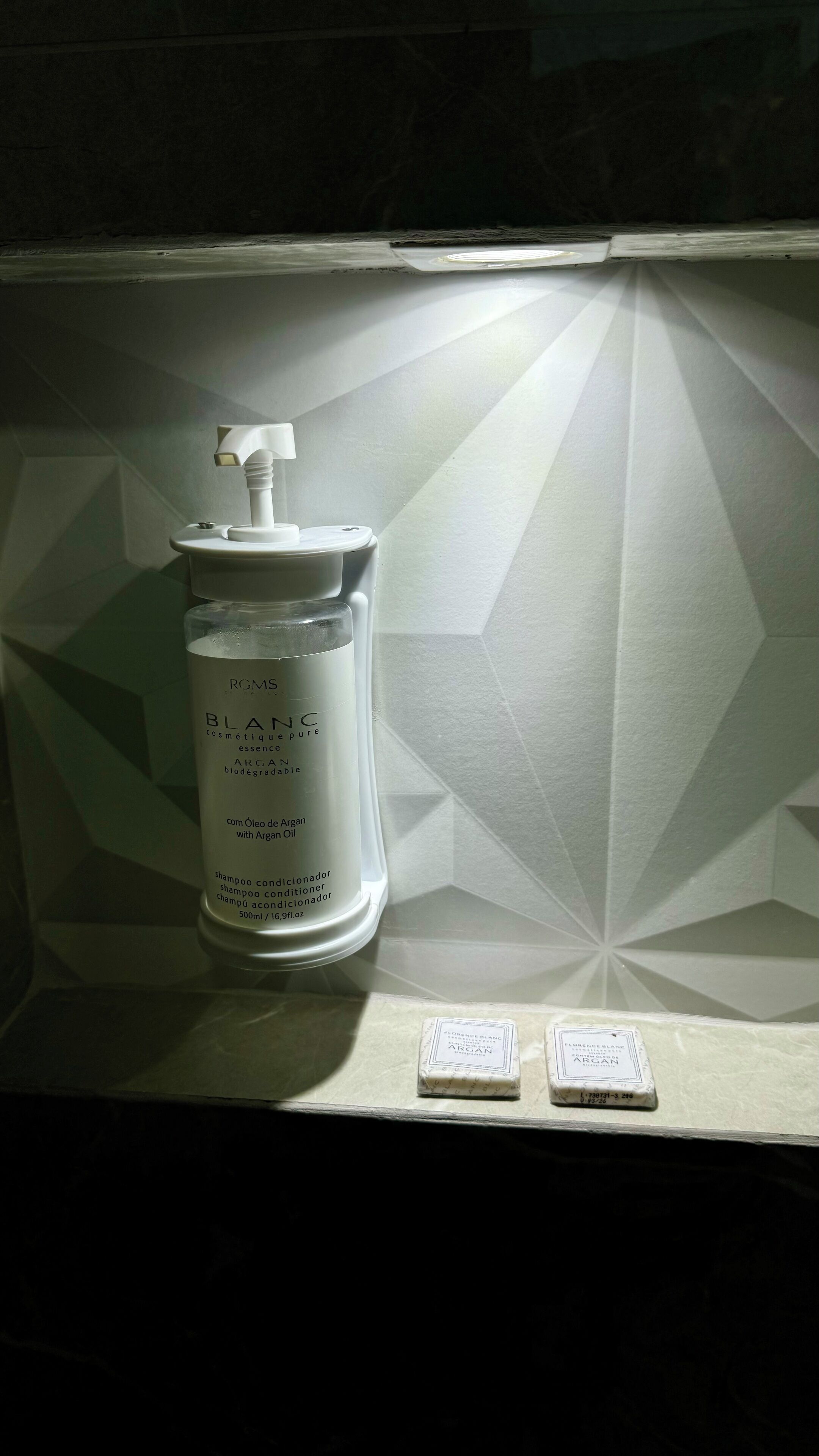 Une salle de bain avec des toilettes blanches, un flacon d’essence cosmétique RGMS BLANC et deux savons sur le comptoir.