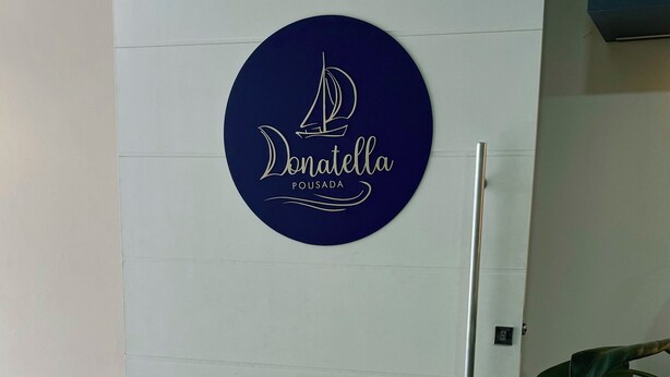 Eine Tür mit einem runden Logo, das ein Segelboot zeigt und den Text "Donatella Pousada" enthält.