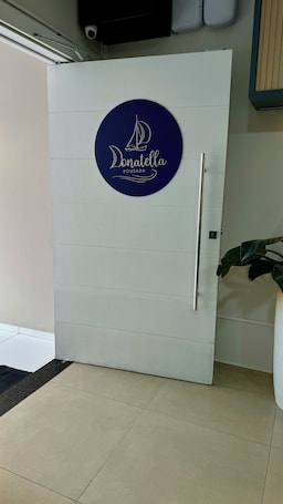 A door with a circular logo featuring a sailboat and the text "Donatella Pousada".