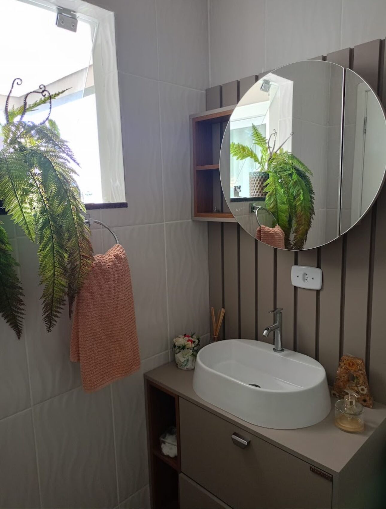 A bathroom with a round mirror, white sink, and a towel hanging on a rack.