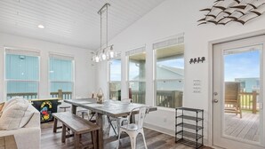 Un vaste espace de salle à manger avec une table et des bancs en bois, de grandes fenêtres et une vue sur la terrasse.