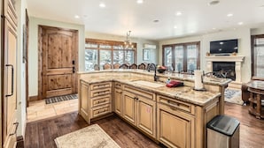 A spacious kitchen with a large island, wooden cabinetry, and a fireplace.