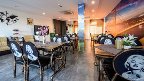 Zona pranzo con tavoli e sedie, una mappa del mondo a parete e un grande murale raffigurante un ponte.