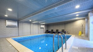 Una piscina interna con acqua cristallina, pavimento piastrellato e soffitto con illuminazione a incasso.