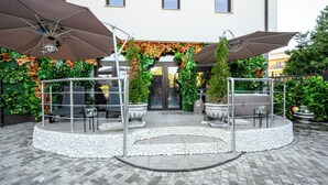 Un'area patio con un'area salotto circolare, ombrelloni da esterno e piante in vaso.
