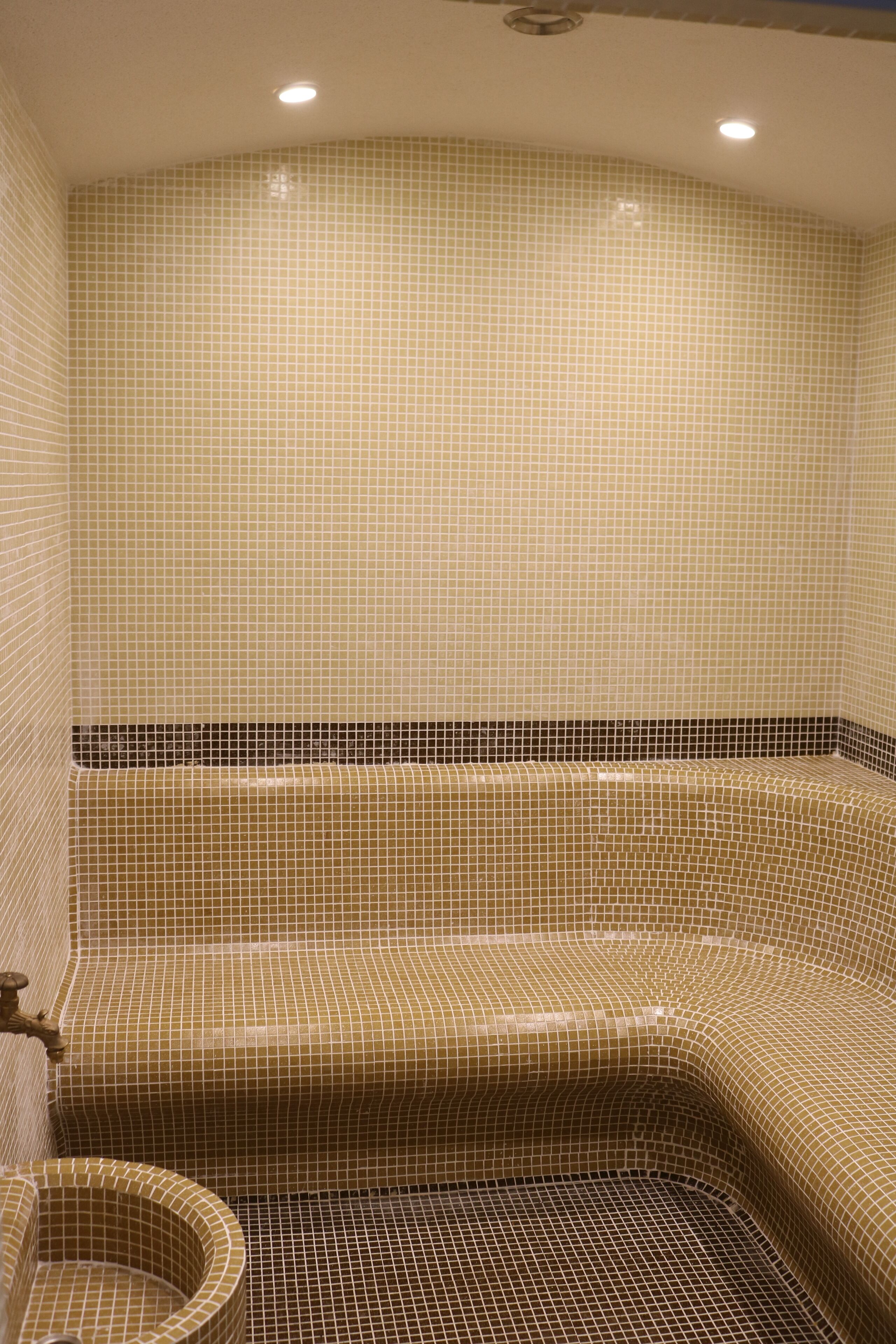 A bathroom with a tiled wall and floor, a bathtub, and a small sink.