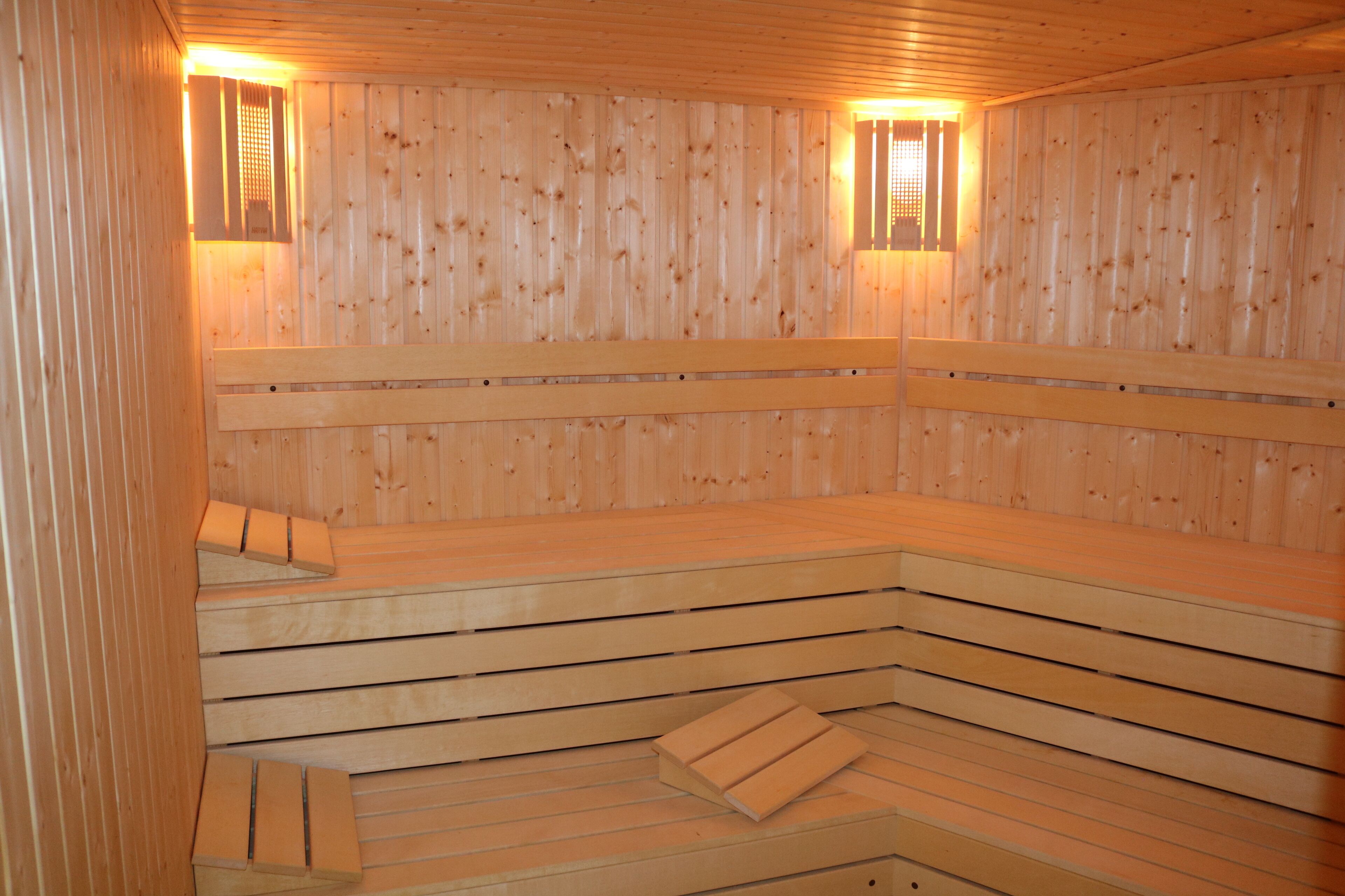 Una sauna con panche e pareti in legno, e due luci fissate al muro.