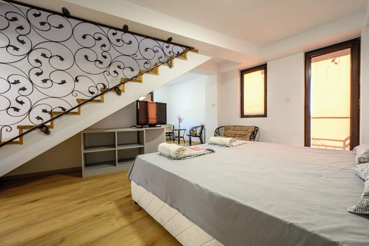 A bedroom with a bed, a desk, a chair, and a staircase.