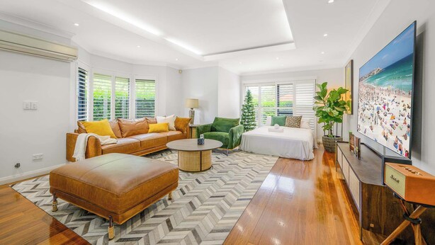 A modern living room with a sofa, ottoman, coffee table, and a TV on a stand. - Maroubra Gem Close to Beach Sleep 16 (Maroubra)