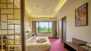 Habitación de hotel con una cama grande, un escritorio, una silla, un televisor y una ventana con vistas a zonas verdes.
