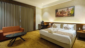 Una habitación de hotel con una cama grande, un sofá, un escritorio y un cuadro en la pared.