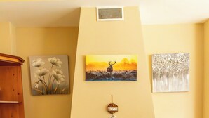 A fireplace with a mantel, a shelf with decorative items, and a painting on the wall.