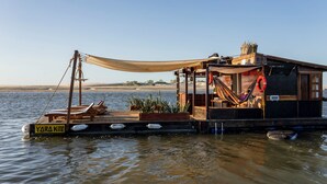 Una casa flotante con terraza, sillones de descanso y toldo.