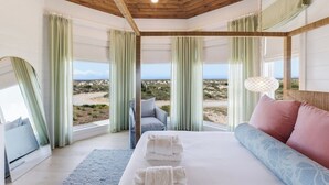 A bedroom with a bed, a sofa, and a view of the beach.
