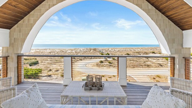 A covered outdoor seating area with a view of the beach and ocean.
