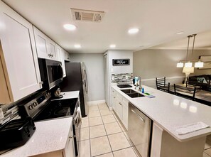 A modern kitchen with white cabinets, stainless steel appliances, a tiled backsplash, and a kitchen island.