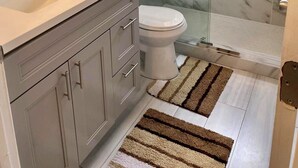 A modern bathroom with a glass-enclosed shower, a marble backsplash, and a vanity with a sink and mirror.