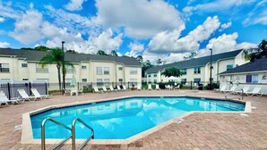 A rectangular swimming pool with a brick deck, surrounded by lounge chairs and a fence. - Grand Disney Somerset 3BR Condo Near Parks (Kissimmee)