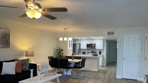 A modern living room with a dining area, a kitchen, and a ceiling fan. - Grand Disney Somerset 3BR Condo Near Parks (Kissimmee)