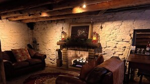 A cozy living room with a stone fireplace, leather sofas, and a rustic wooden ceiling. - c1815, 3-bedroom Bed & breakfast in charming Historic Brownsburg with WiFi, AC (Rockbridge Baths)