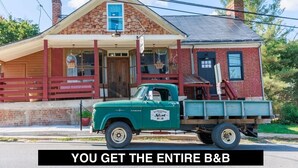 A vintage green truck parked in front of a brick building with a porch and a sign that reads "Old Brown's". - c1815, 3-bedroom Bed & breakfast in charming Historic Brownsburg with WiFi, AC (Rockbridge Baths)