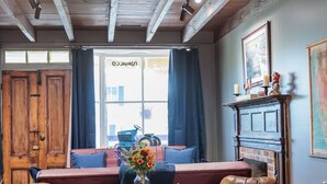 A cozy room with wooden beams, a fireplace, a sofa, two leather chairs, and a small table with a vase. - c1815, 3-bedroom Bed & breakfast in charming Historic Brownsburg with WiFi, AC (Rockbridge Baths)