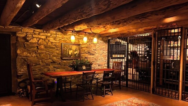 A rustic dining area with stone walls, wooden furniture, and a patterned rug. - c1815, 3-bedroom Bed & breakfast in charming Historic Brownsburg with WiFi, AC (Rockbridge Baths)