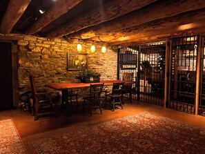 A rustic dining area with stone walls, wooden furniture, and a patterned rug.