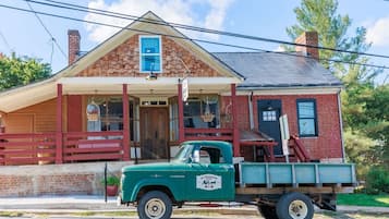 Un vieux camion vert est garé devant un bâtiment en briques, doté d’un porche et d’une enseigne sur laquelle on peut lire « Old Brown’s ».