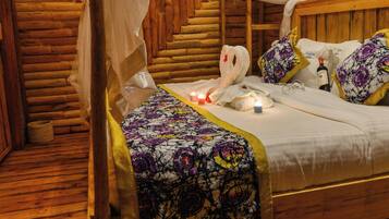 A wooden bed with a canopy, floral bedding, and a candle on the nightstand.