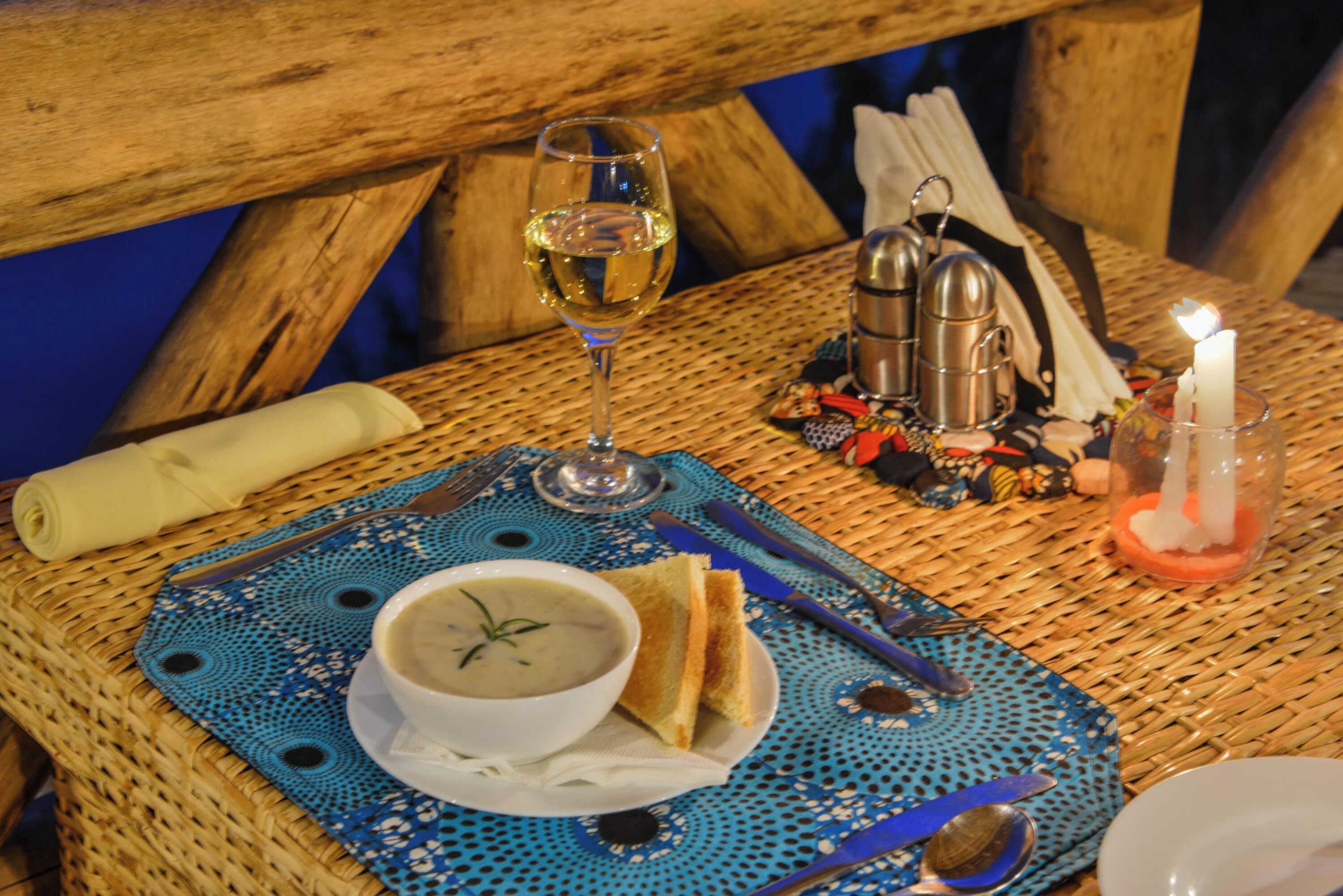 Ein Esstisch mit einer Suppenschüssel, einem Glas Weißwein und einer Kerze.