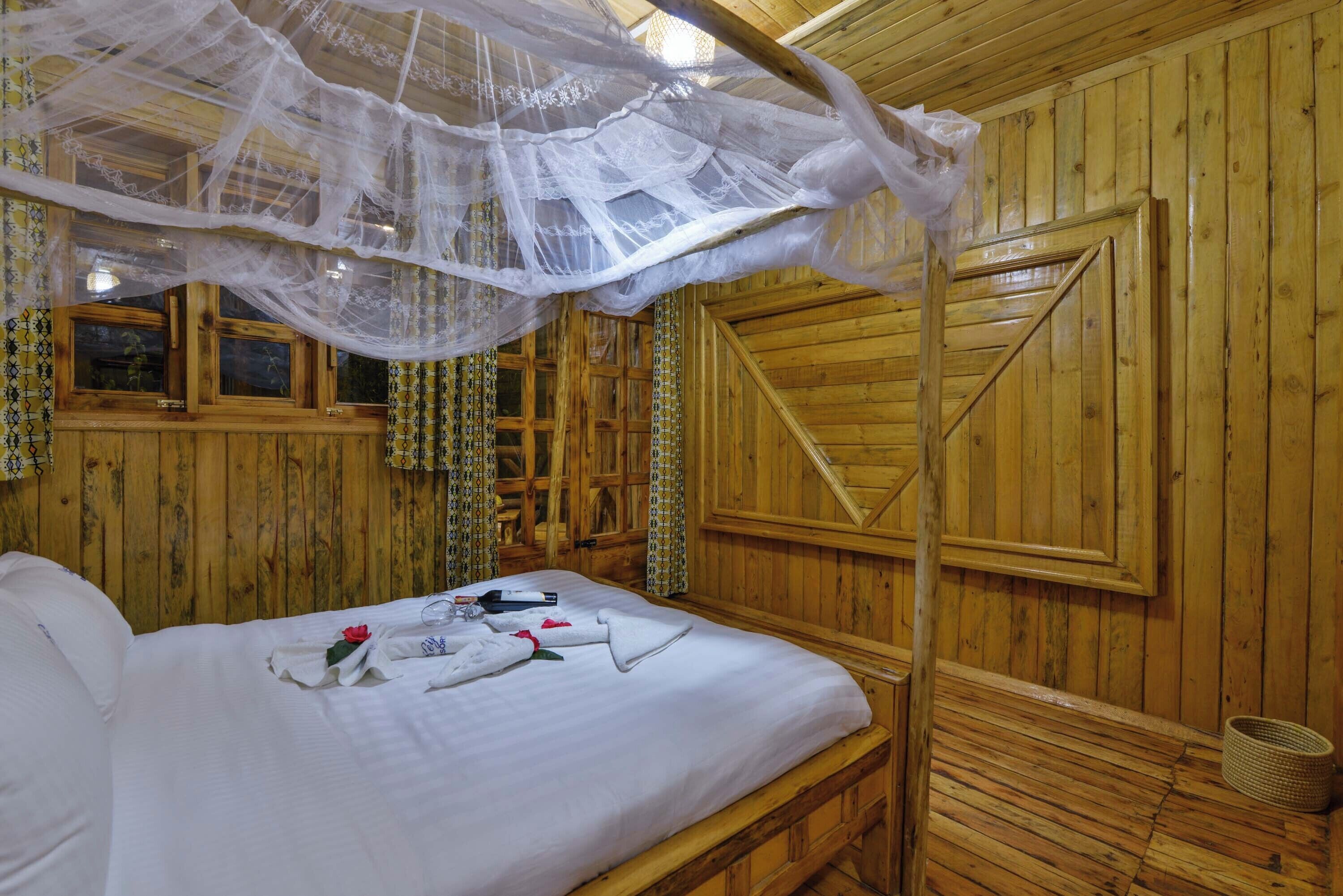 Una habitación de madera con una cama, un dosel y una puerta de madera.
