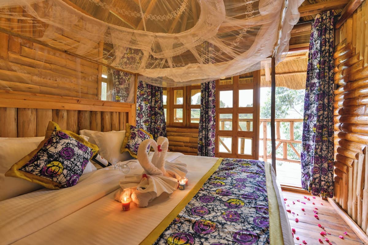 Ein Holzhütten-Zimmer mit einem Bett, blumigen Vorhängen und einem Baldachin.