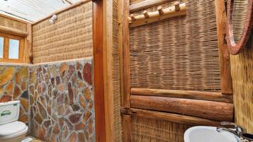 A bathroom with a stone wall, a wooden door, and a white sink.