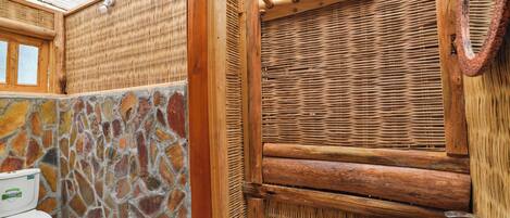 Un baño con pared de piedra, puerta de madera y lavamanos blanco.