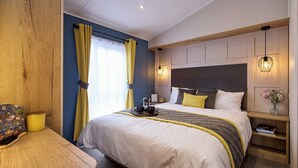 A hotel room with a bed, bedside table, and a small desk with a chair.