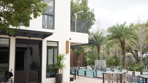 A modern outdoor patio with a pool, seating area, and a two-story building with large windows and a balcony. - Feeling Hotel (Beinan)