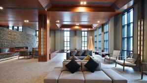 A spacious lobby with a large sectional sofa, multiple seating areas, and a stone accent wall. - Feeling Hotel (Beinan)