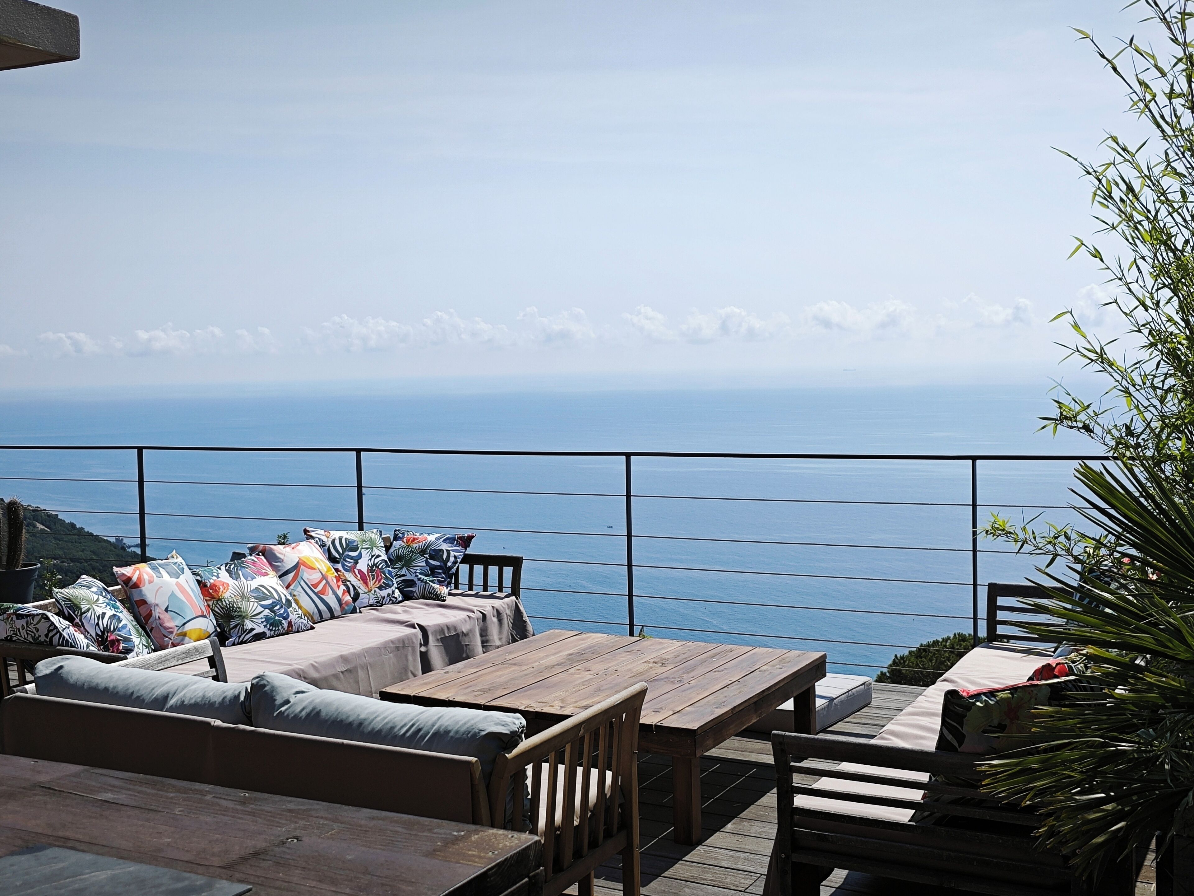 Une terrasse en bois avec un canapé et des fauteuils, une table et une vue sur l’océan.