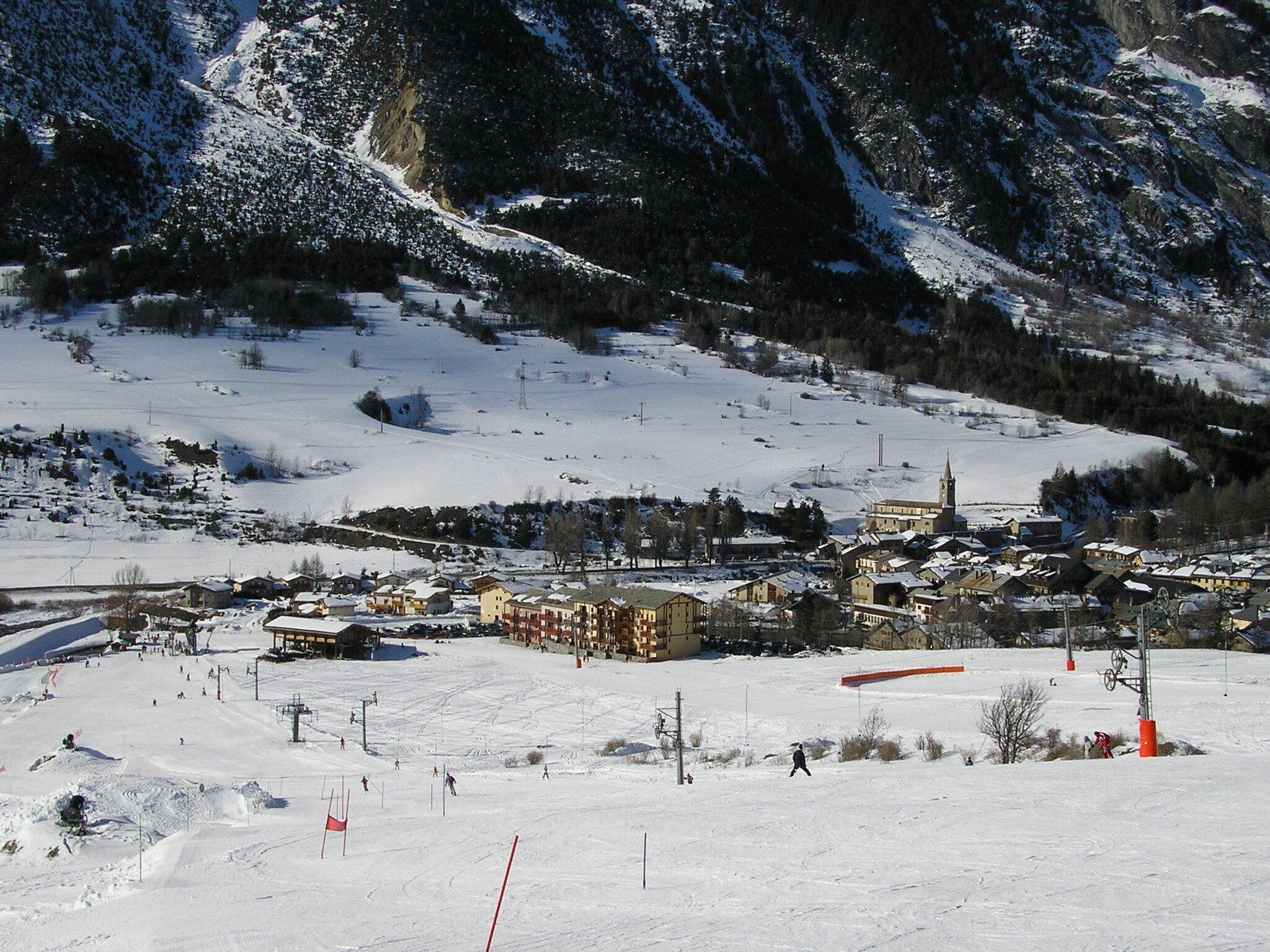 A snow-covered mountain town with buildings, a church, and ski slopes.