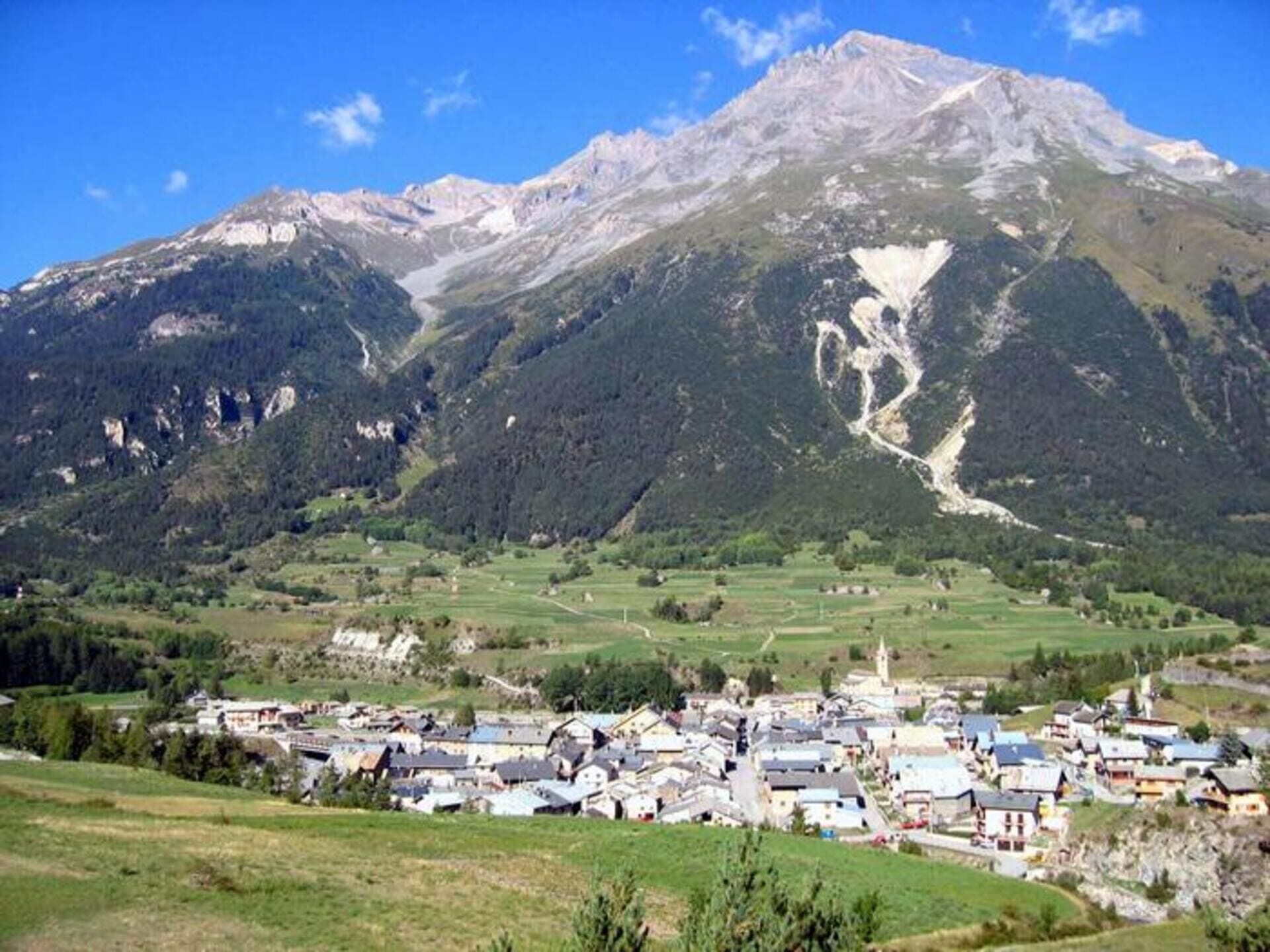 A mountain village with traditional houses, a church, and a valley.
