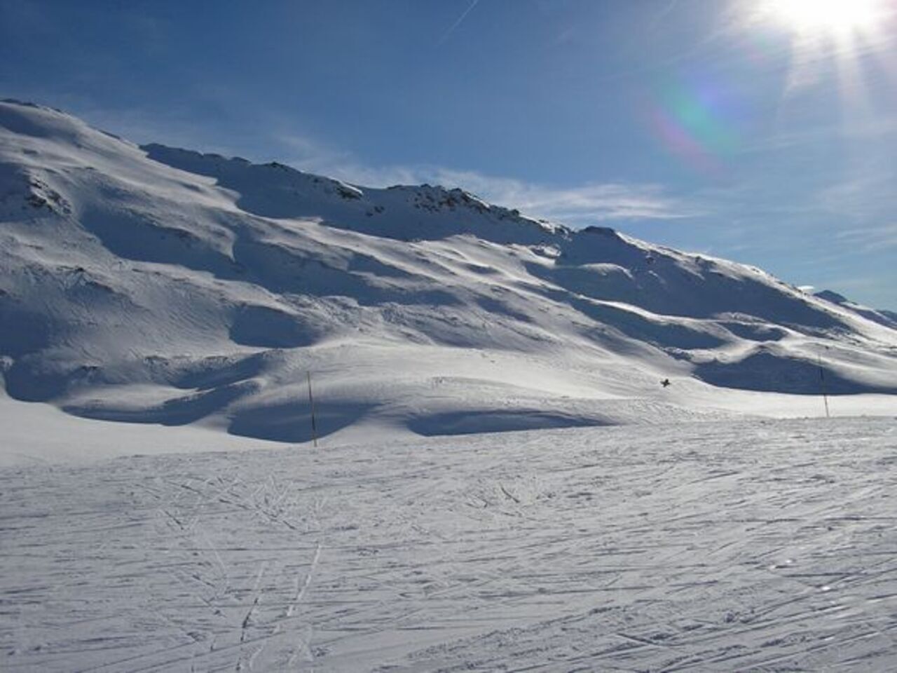 A snowy mountain landscape with a clear sky and sunlight.