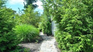 A stone pathway leading through a lush garden with dense green foliage on both sides. - (3 Nt Summer Min!) Union Pier Condo With Heated Pool! July 04-10 OPEN! (Union Pier)