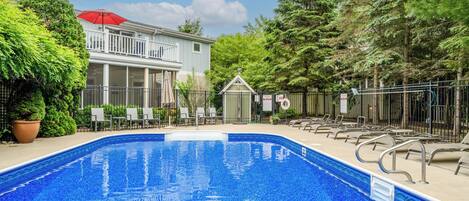 A swimming pool with lounge chairs and a small gazebo.