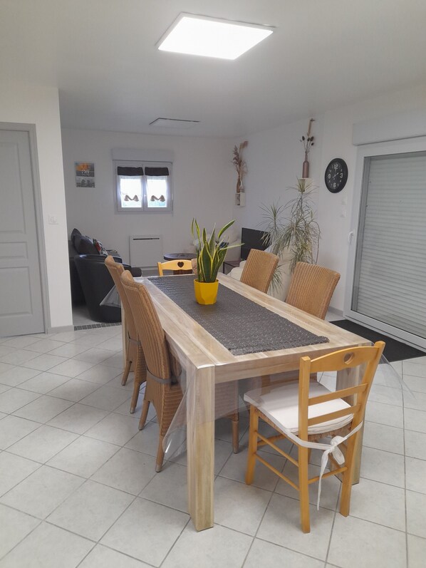 Un área de comedor con una larga mesa de madera, seis sillas y una planta en maceta.